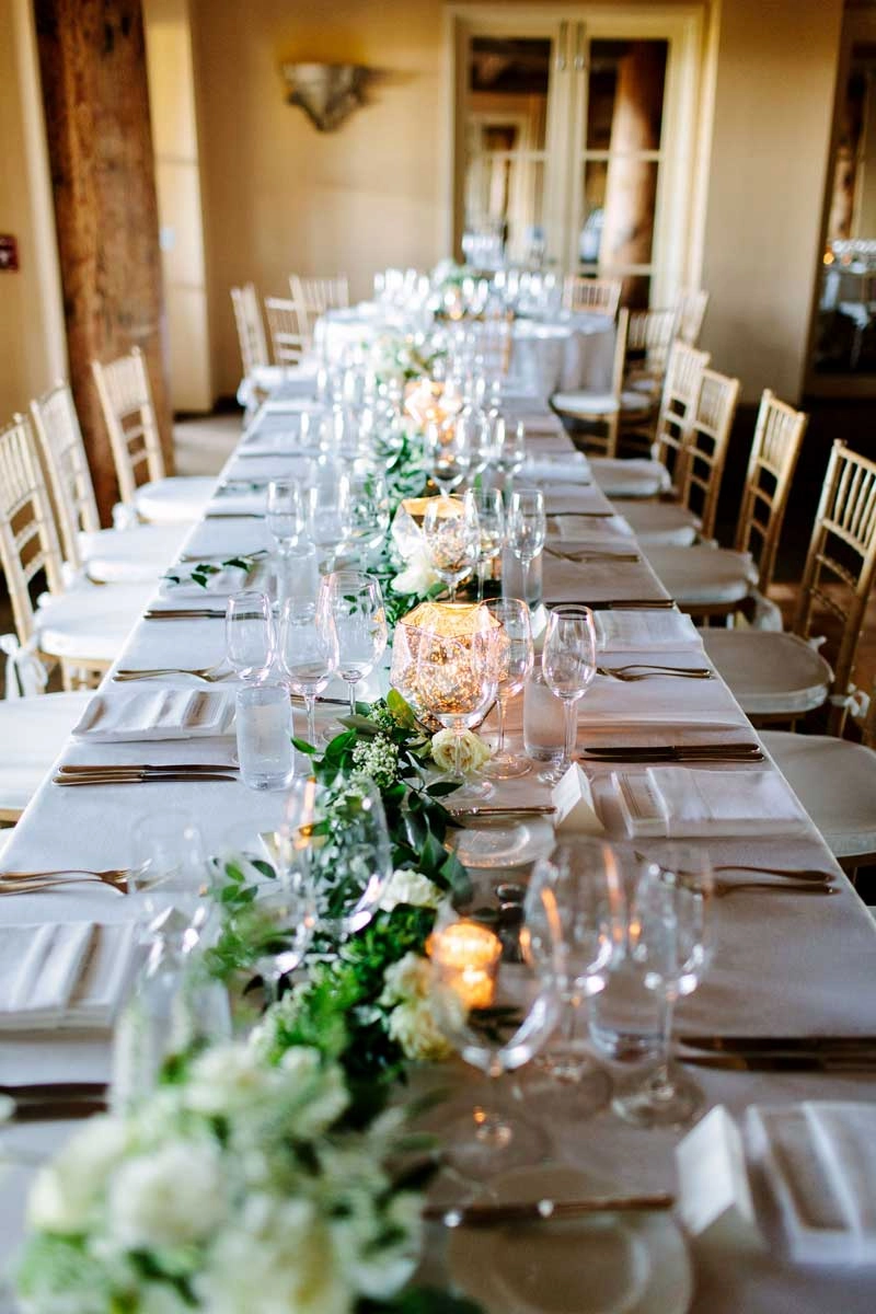 Long banquet table with a trailing greenery and white rose runner
