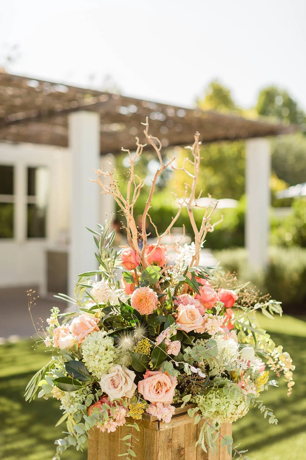Peach garden rose and hydrangea pedestal arrangement on a wooden plinth