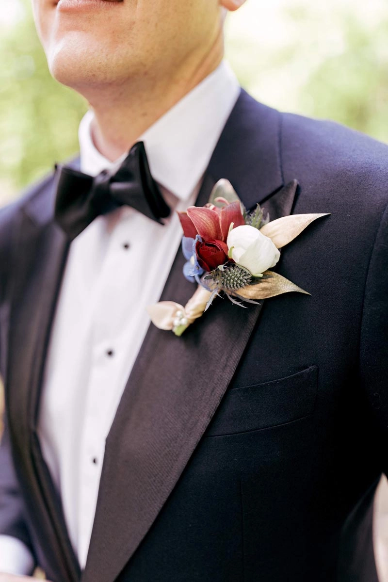 Boutonnière of ranunculus and thistle on a tuxedo lapel