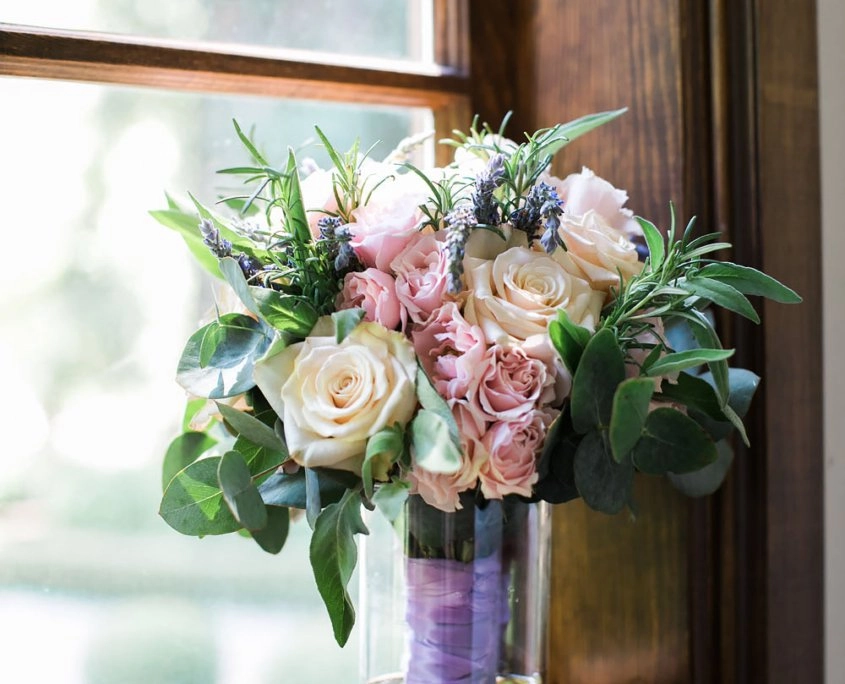 Blush rose and lavender bouquet in a ribbon-wrapped vase by a window